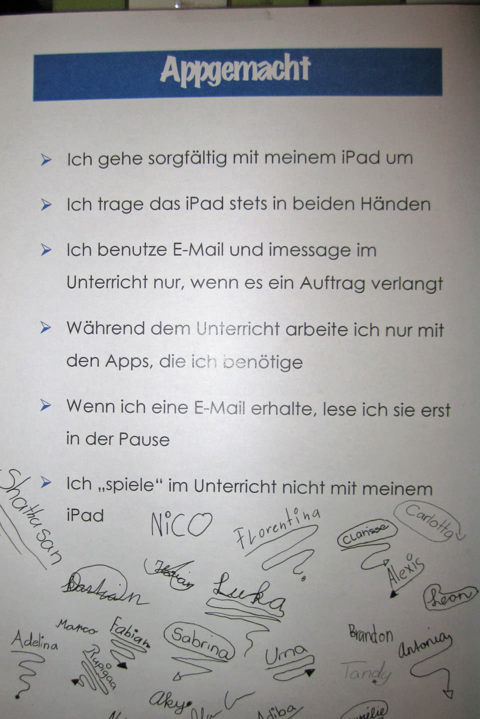 Ein Blatt mit fünf Regeln für den Umgang mit dem iPad, darunter die Unterschriften der Kinder.