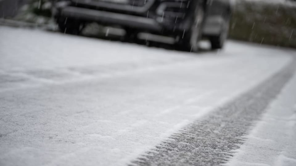 Schneebedeckte Strasse, Auto verschwommen im Hintergrund