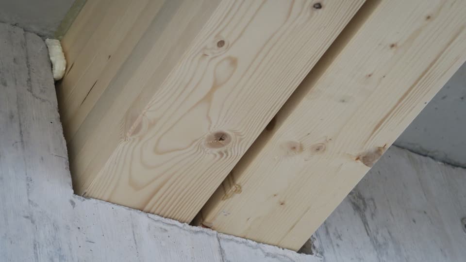 Holzbalen verschwinden in die Betonmauer.