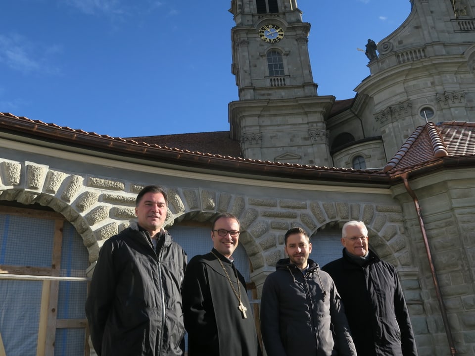 Vier Männer vor Klosterkirche.