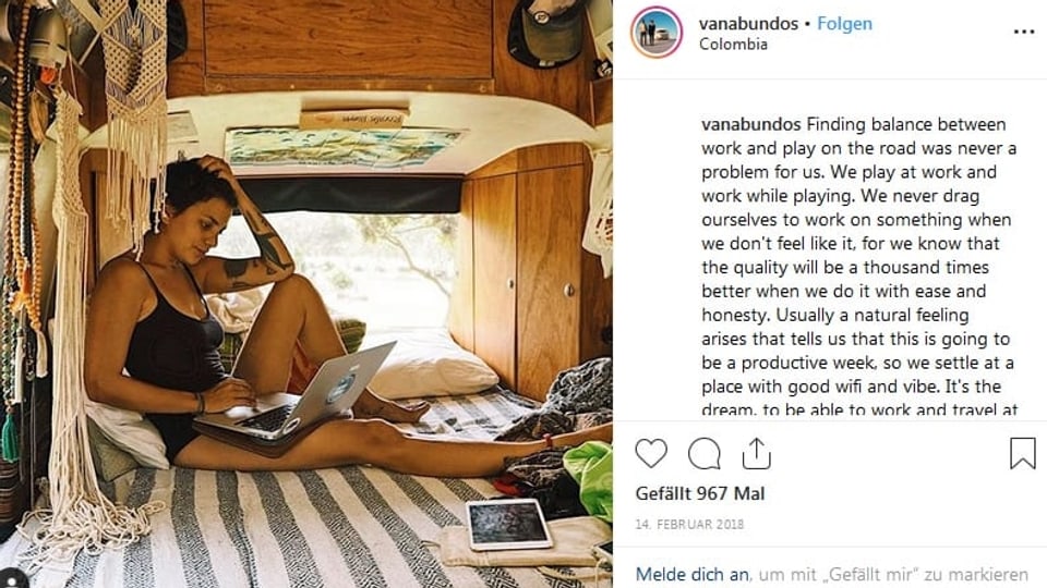 Junge Frau sitzt auf Matratze in einem VW-Bus und arbeitet am Laptop.