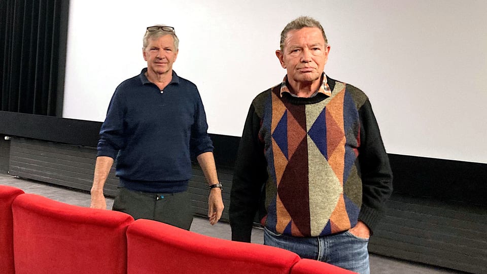Alban and Adrian Hürlimann stand between the screen and the cinema seats.
