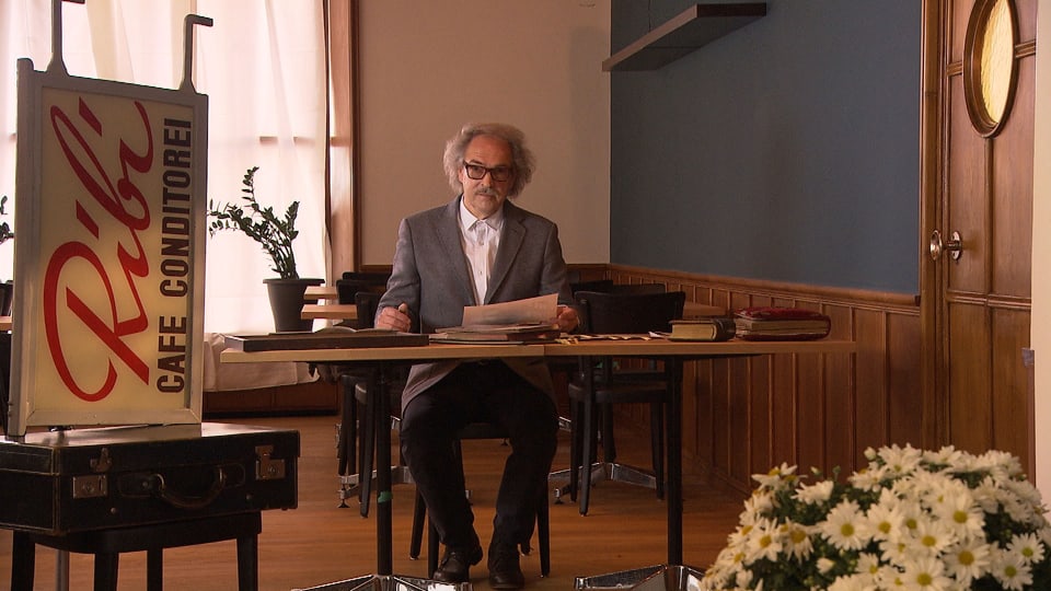 Emil Ribi sitzt an einem Tisch in einem historischen Raum
