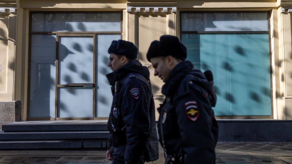 Zwei Polizisten gehen in Russland an einer Boutique vorbei.