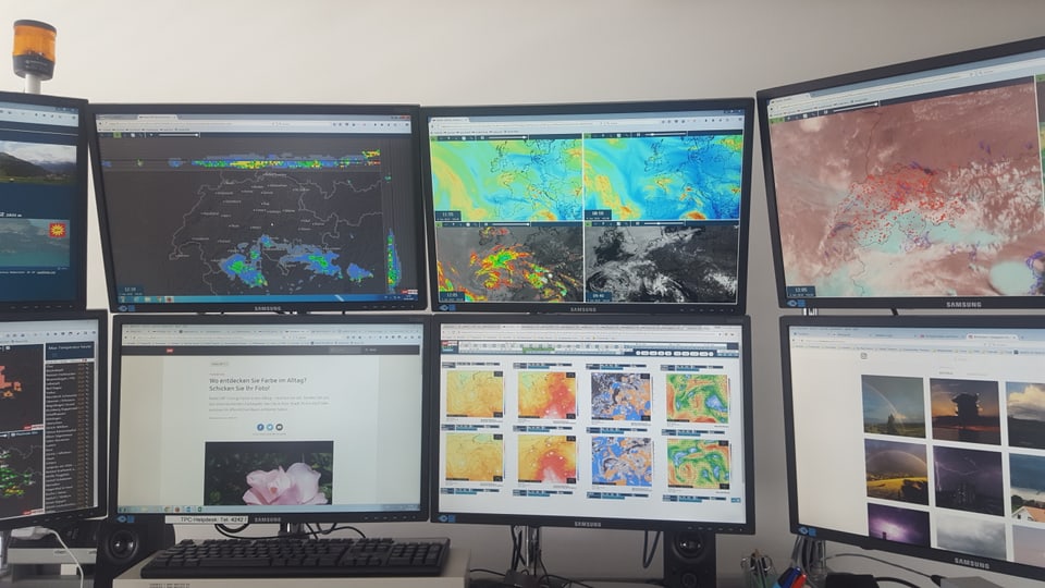 Der Arbeitsplatz mit vielen Bildschirmen mit Wetterkarten.