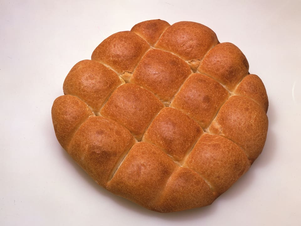 Ein runder Laib Brot, der in mehrere kleine Stücke unterteilt ist.