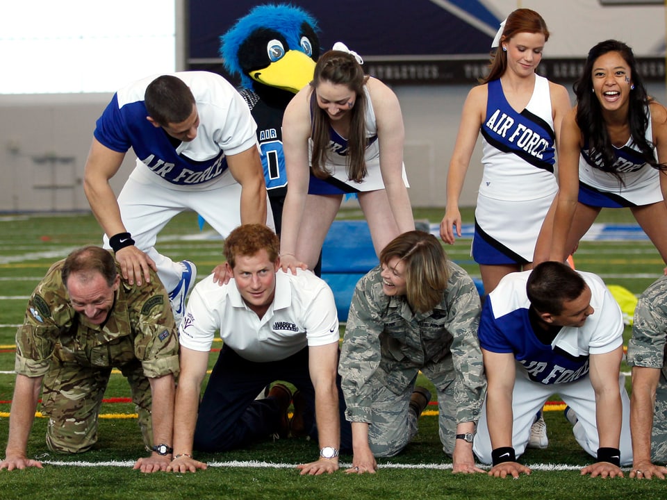 Prinz Harry macht auch als männlicher Cheerleader eine gute Figur. Beim Air Force-Footballteam in Colorado lässt er sich für eine menschliche Pyramide einspannen.