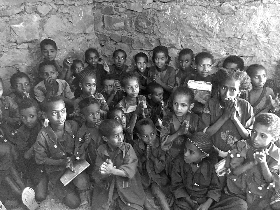 Schwarz-weiss-Foto: Kinder sitzen am Boden in einer Ecke.