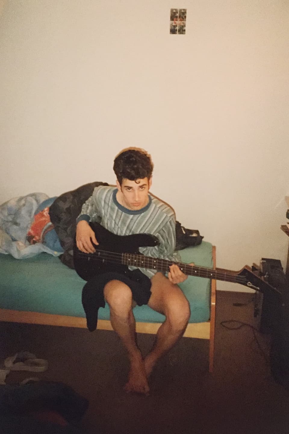 Philippe Gerber spielt im Pyjama auf dem Bett sitzend Gitarre.