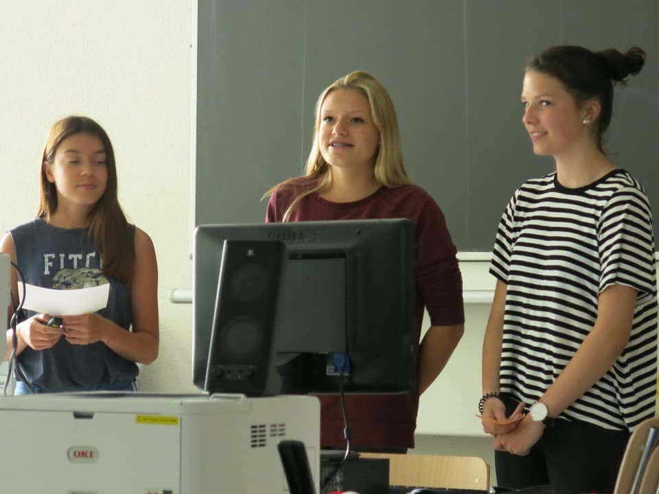 Drei Mädchen stehen vor der Klasse und sprechen. 