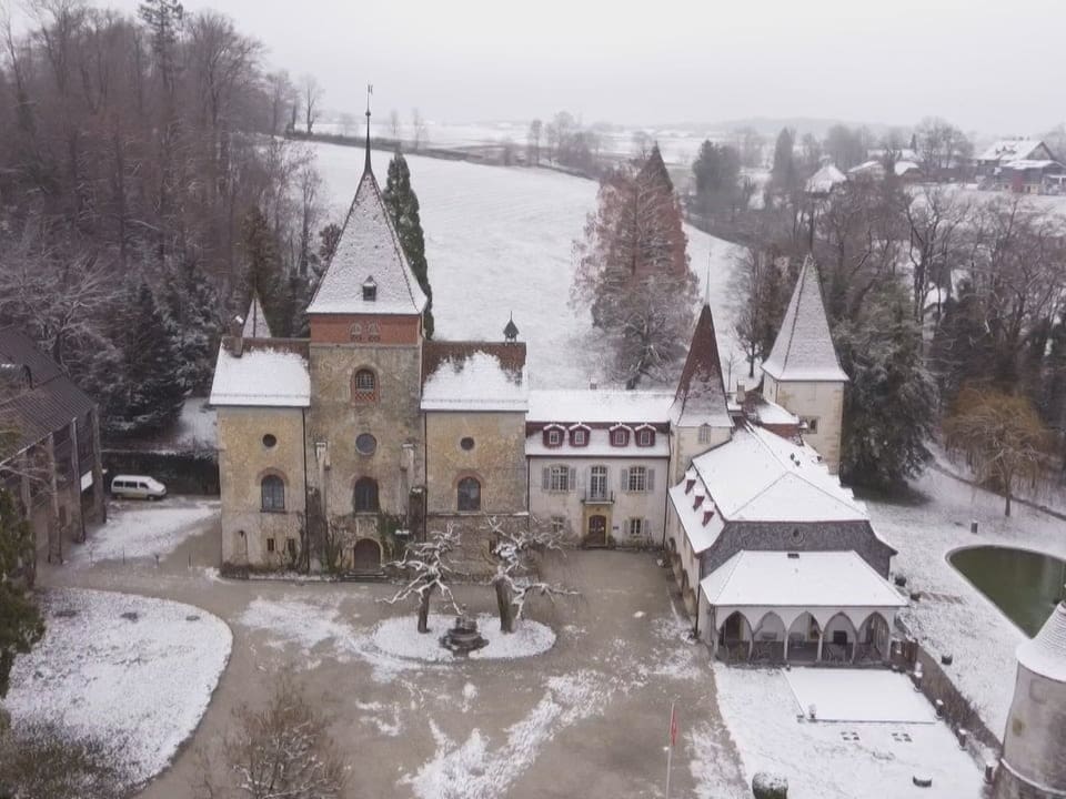 Drohnenaufnahme des Schlosses Münchenwiler: Der grosse Innenhof ist leer. Schnee liegt auf den Türmen und im Garten.