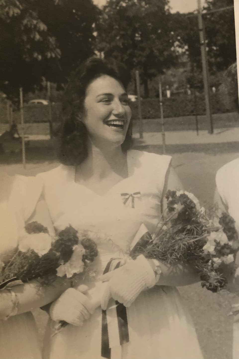 Eine lachende Frau hält einen Blumenstrauss in der Hand.