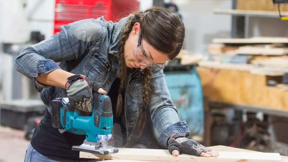 eine Frau sägt ein Holzbrett