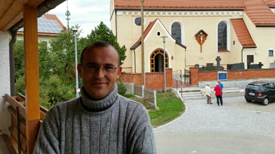 Hassan Hammed lächelnd vor einer Kirche. 