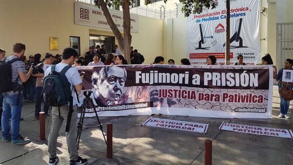 Angehörigen der Toten protestieren mit einem Transparent Fujimori a Prision.