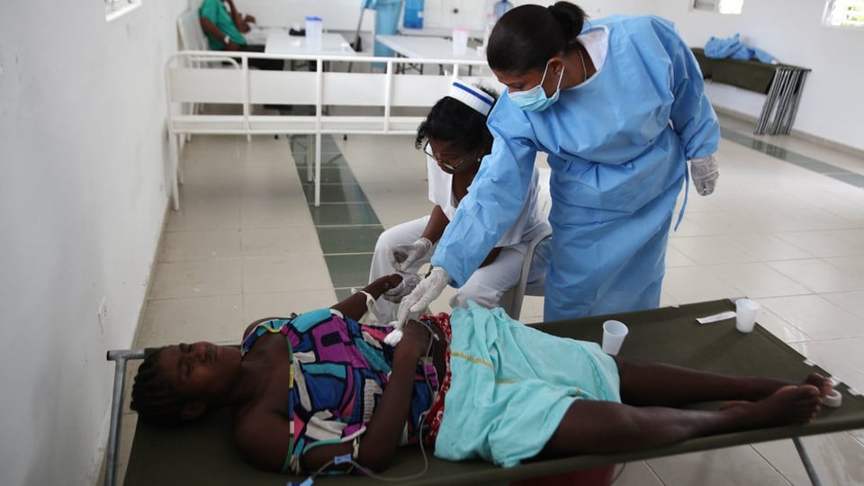 Cholera-Patientin wird von zwei Pflegerinnen gepflegt