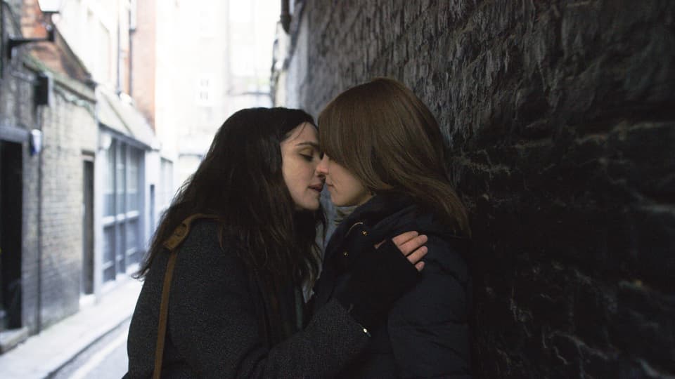 Zwei Frauen küssen sich, sind an eine Mauer angelehnt.