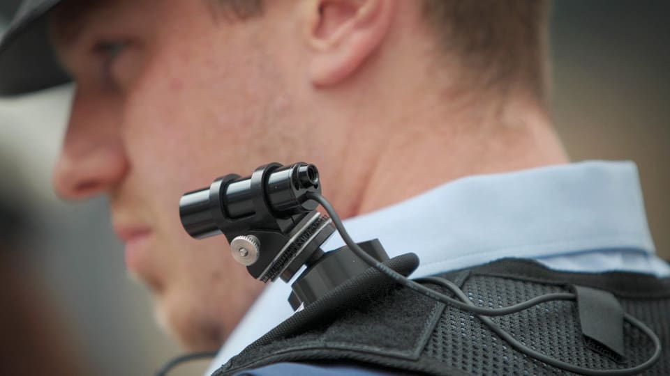 Ein Polizeibeamter mit einer Bodycam auf der Schulter.