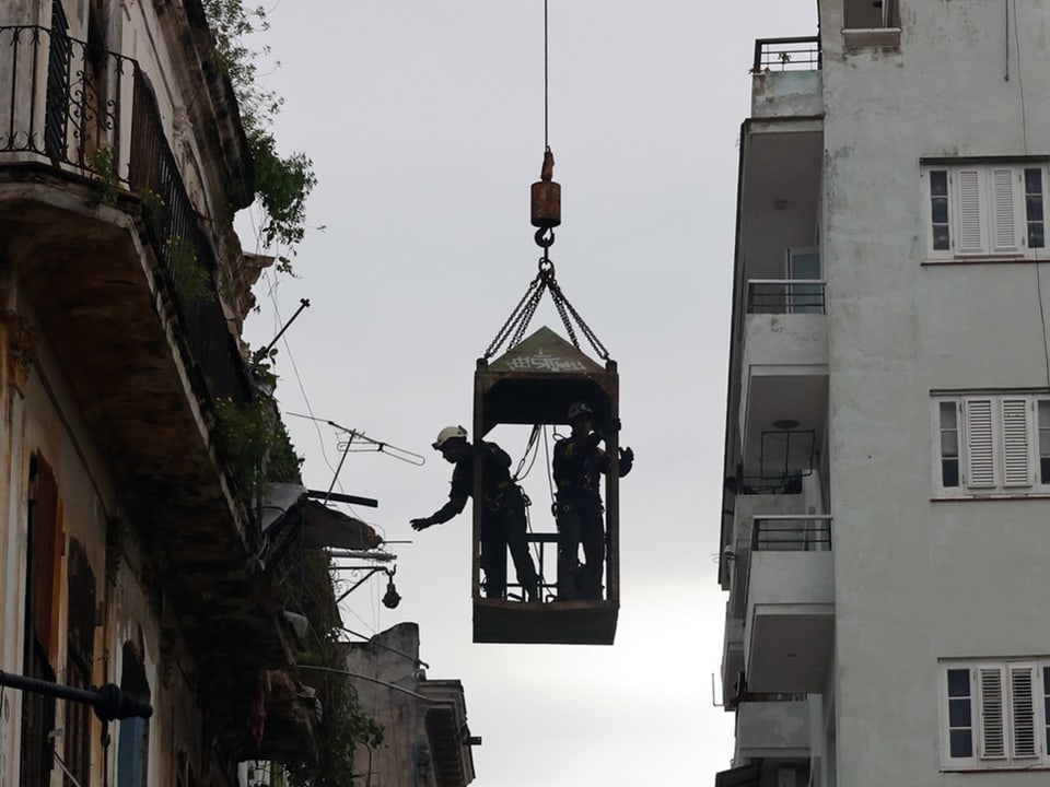 Rettungsarbeiter in einer Kapsel, die von einem Kran in die Luft gezogen wird.