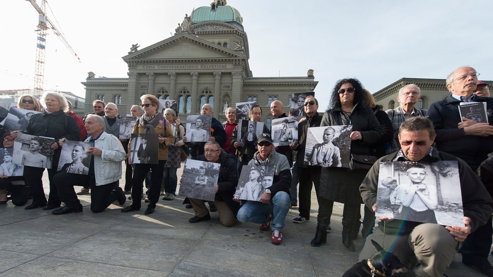 Ehemalige Verdingkinder und Opfer von fürsorgerischen Massnahmen posieren mit Kinderfotos vor dem Bundeshaus am 31.3.2014