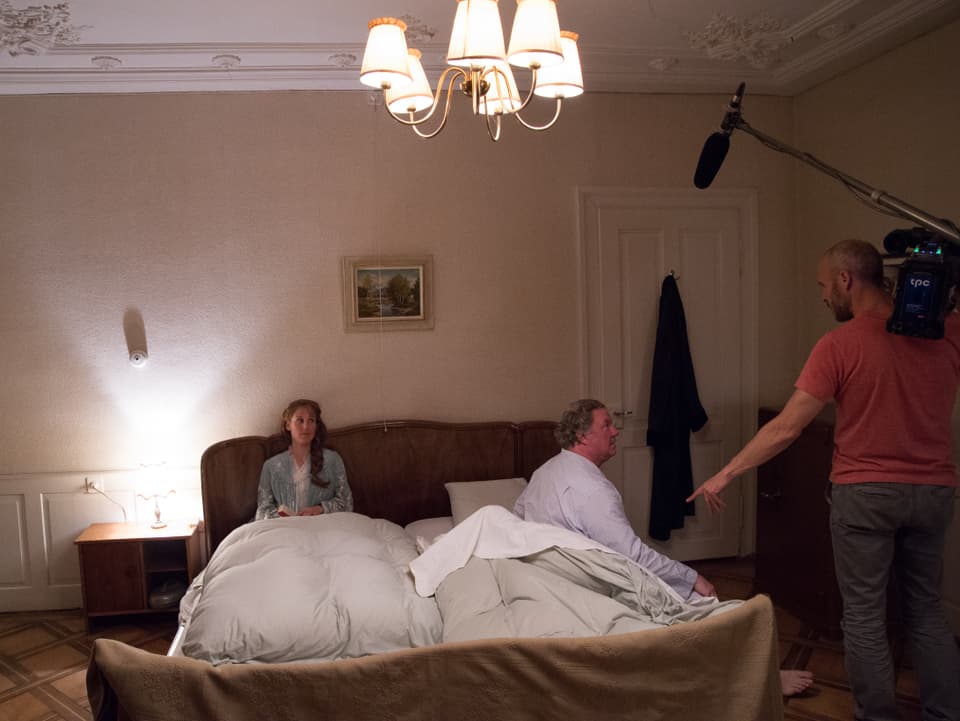 Zwei Schauspieler im Bett, Kameramann gibt Anweisungen