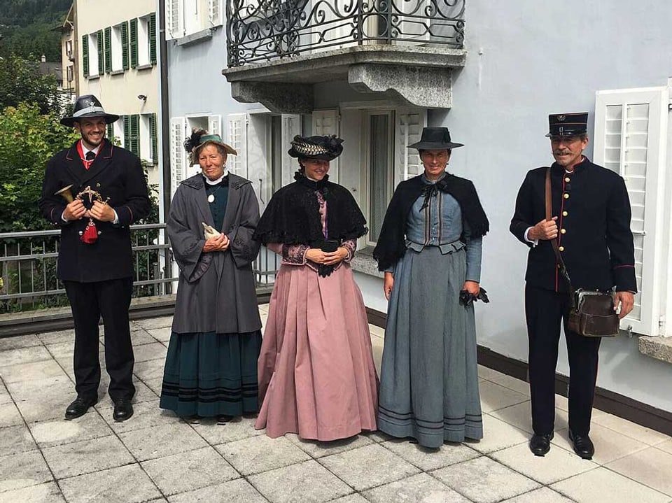 Fünf Personen stehen in historischen Kostümen vor einem Haus.