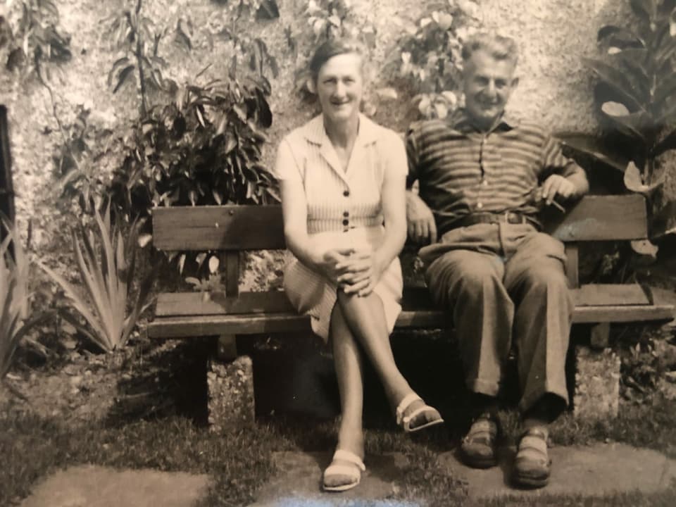 Eine Frau sitzt mit ihrem Mann auf einer Bank.