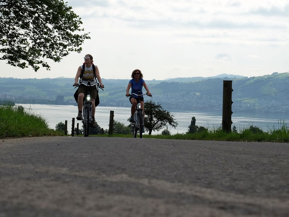 Zwei Frauen auf dem E-Bike, im Hintergrund der Zugersee.