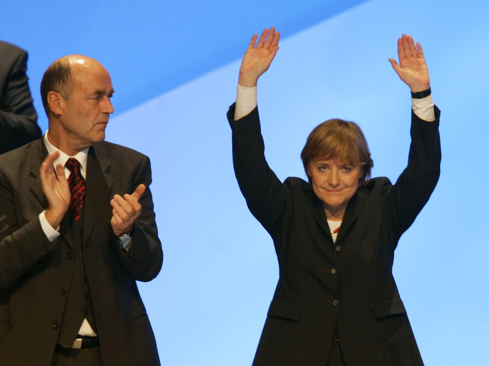 Laurenz Meyer applaudiert Angela Merkel, die beide Hände in die Höhe streckt.