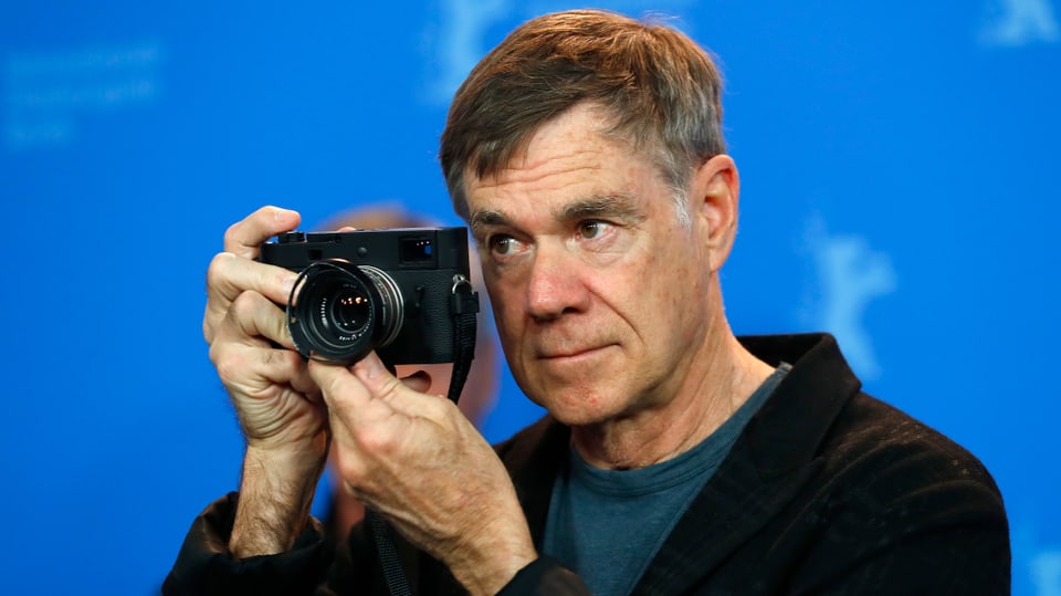 Nahaufnahme des Berlinale-Stammgasts Gus Van Sant mit einer Fotokamera in der Hand.