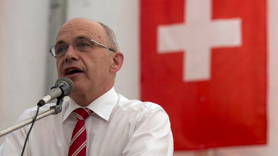Bundespräsident Ueli Maurer vor dem Mikrofon. Im Hintergrund die Schweizer Fahne. 