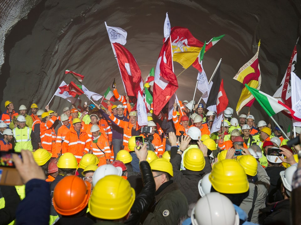 Bergbauarbeiter mit gelben und orangenen Helmen in Schutzkleidung, Fahnen.