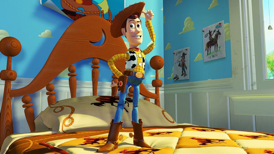 Spielzeugfigur Woody steht auf einem Bett.