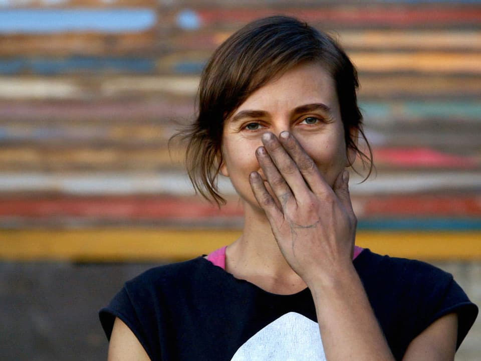 Eine junge Frau hält sich ihre schmutzige Hand vor das Gesicht.