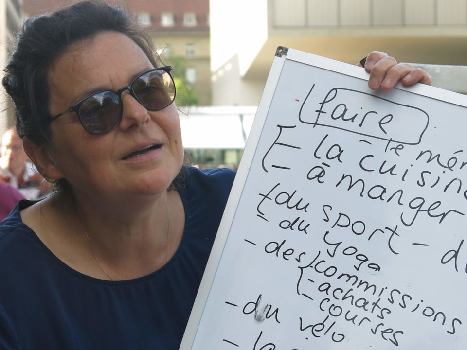 Kursleiterin Marie Lebouteiller mit einem Whiteboard in den Händen.