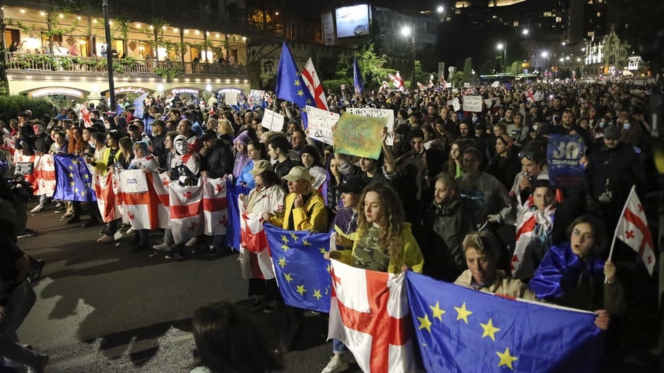 Nachtliche Demonstration mit Menschen, die EU- und diverse Nationalflaggen halten