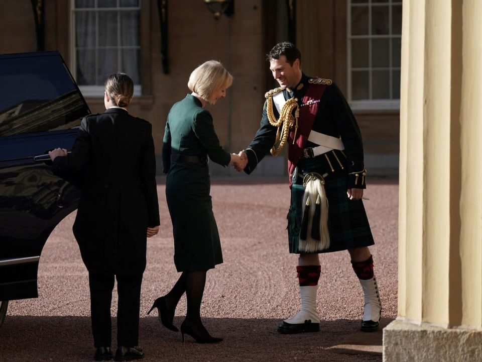 Liz Truss schüttelt einem Mann in Tracht die Hand vor dem Buckingham-Palast.