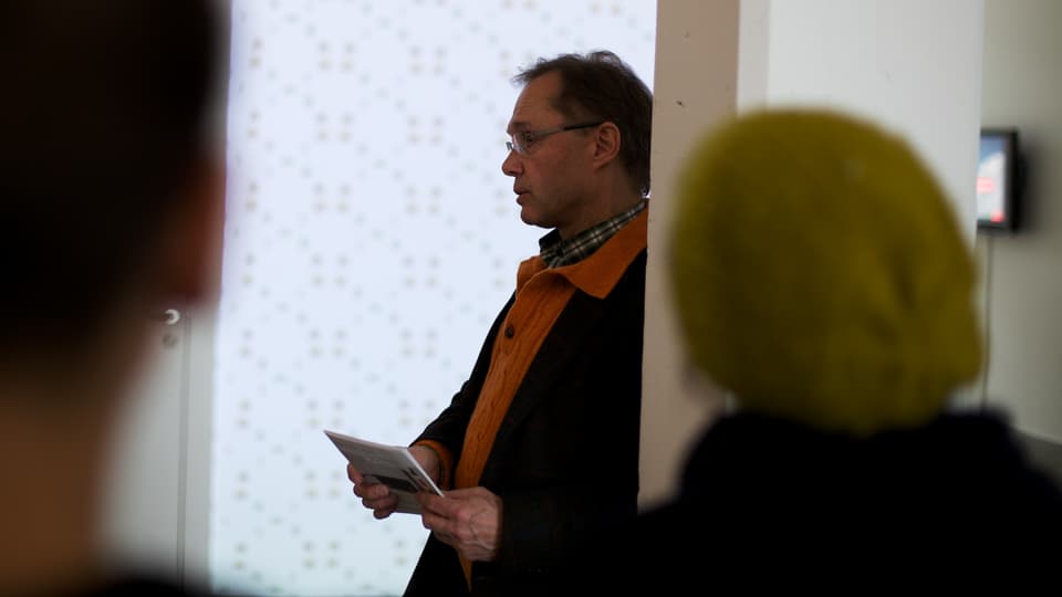 Ein Mann steht mit Notizzettel in der Hand vor Publikum