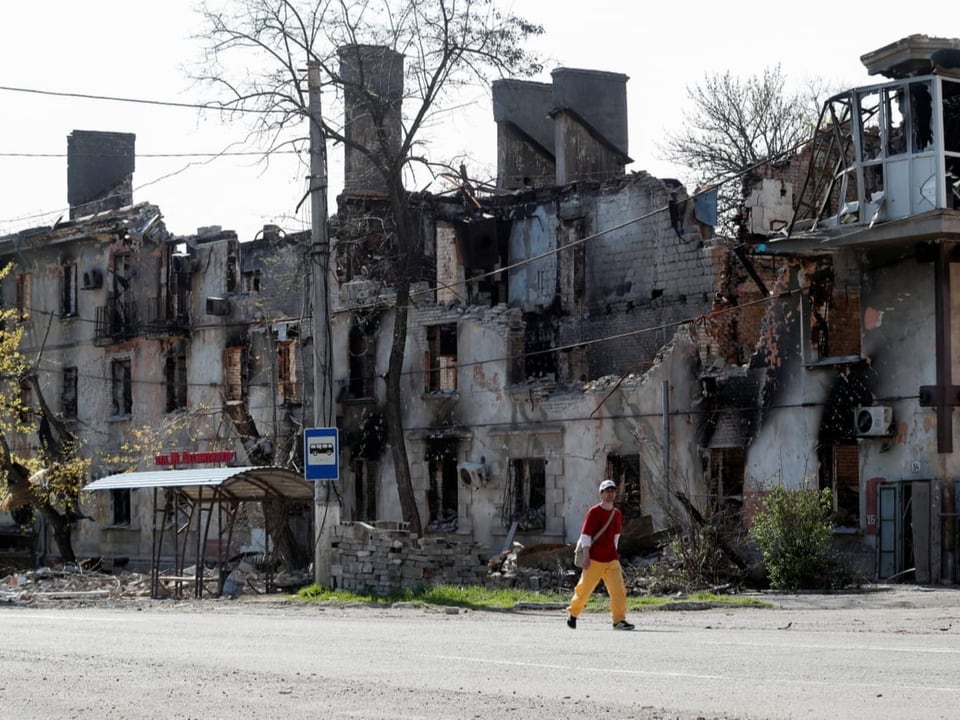 Ein Mann läuft vor einem zerstörten Gebäude in Mariupol vorbei.