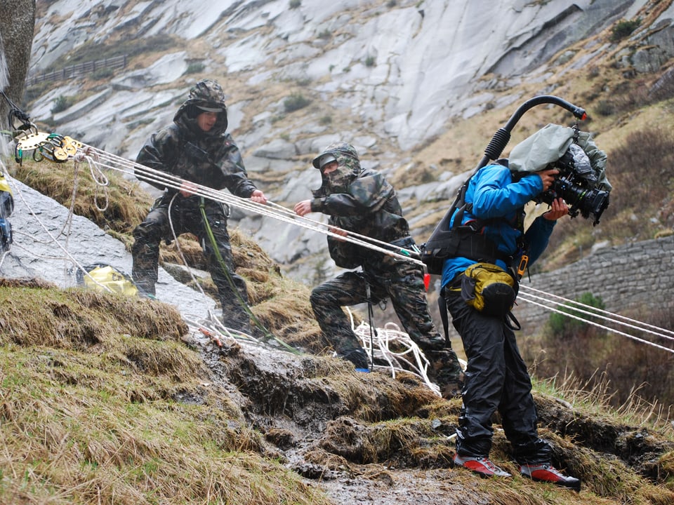 Bergretter der Schweizer Armee richten eine Seilrettung ein. Der Kameramann begleitet sie dabei. 