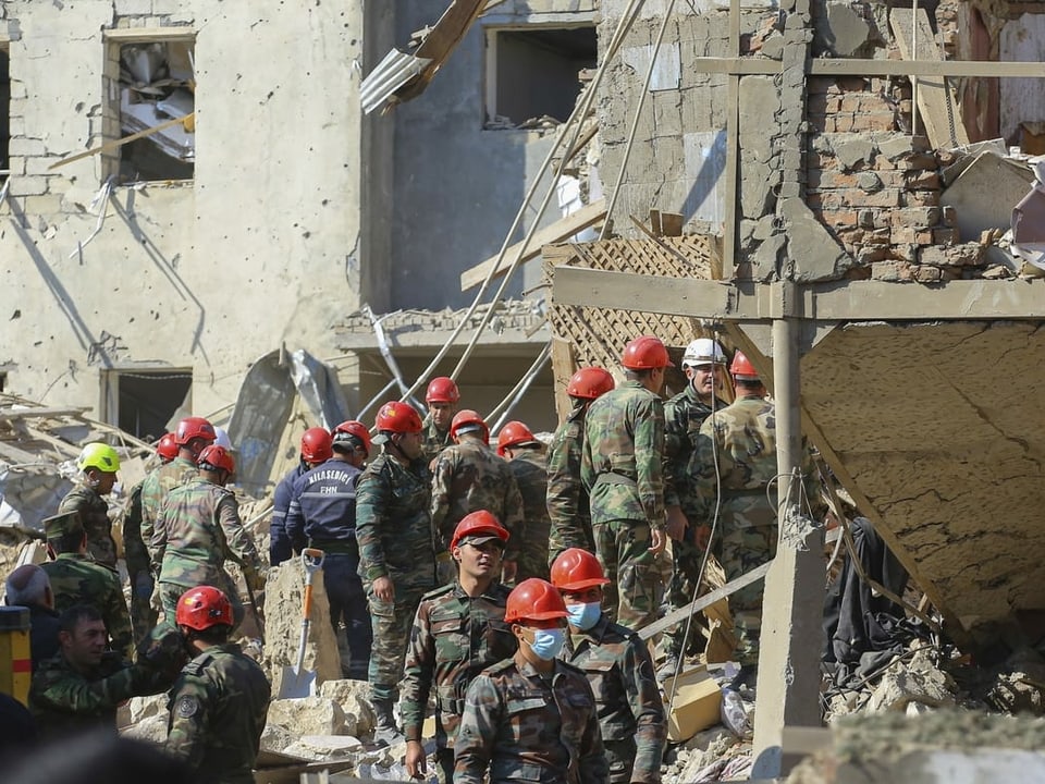 Aserbaidschanische Rettungskräfte räumen an einem zerstörten Haus Trümmer weg.