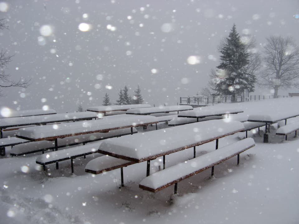 Schneefall auf dem Napf. Es liegen einige Zentimeter Neuschnee auf den Tischen und Bänken.