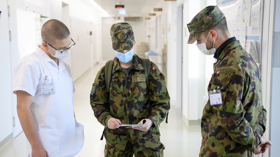 Zwei Armeeangehörige sprechen mit einem Pfleger.