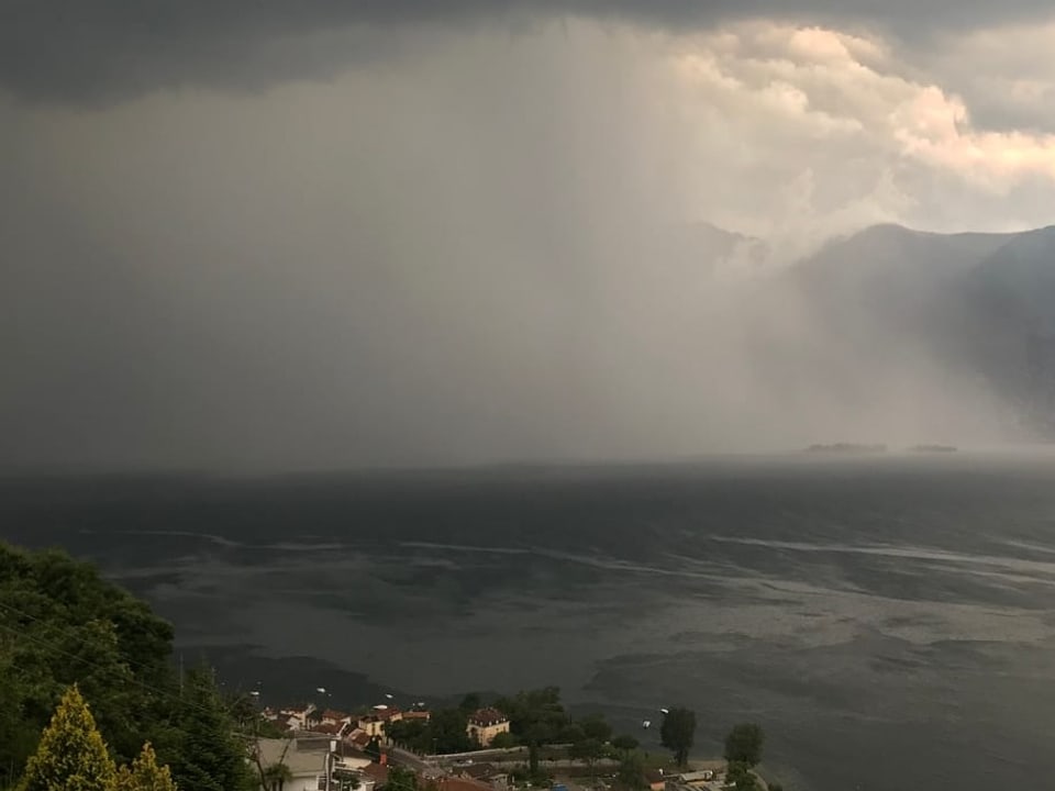 Starker Gewitterregen über einem See im Tessin