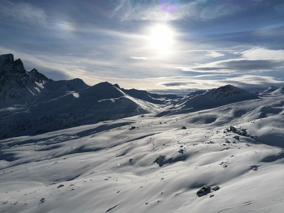 Blick auf ein verschneites Skigebiet mit Schleierwolken am Himmel.