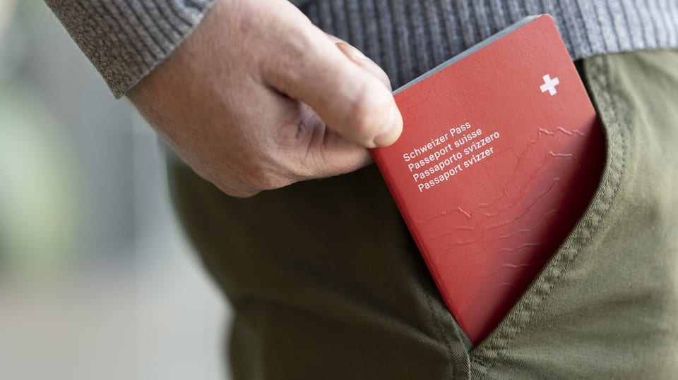 Nahaufnahme einer Hand, die einen roten Schweizer Pass aus der Hosentasche zieht.