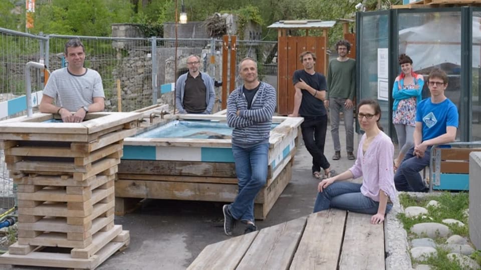 Menschen baden nachts in einem provisorischen Thermalbad neben einem Fluss.