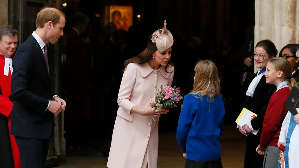 Prinz William und Herozgin Catherine stehen vor Kindern und sprechen mit ihnen.