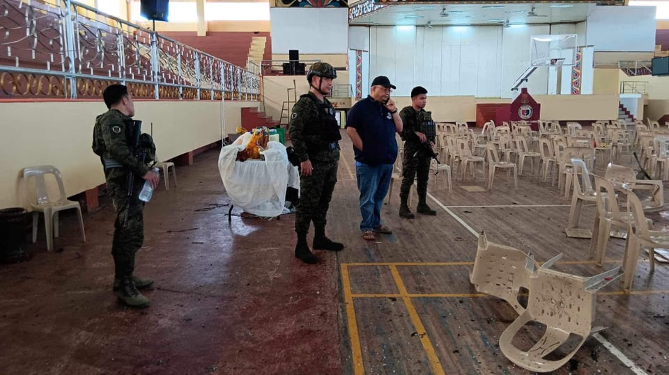 Blick in einen grossen Raum, umgeworfene Plastikstühle, Militär und eine Zivilperson, die telefoniert