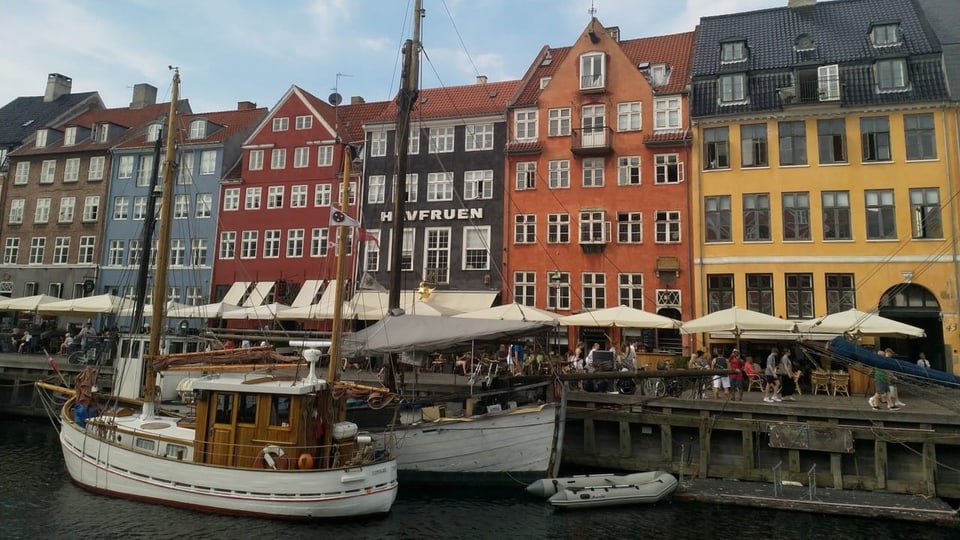 farbige Häuser an einem Pier. Alte Schiffe haben geankert.